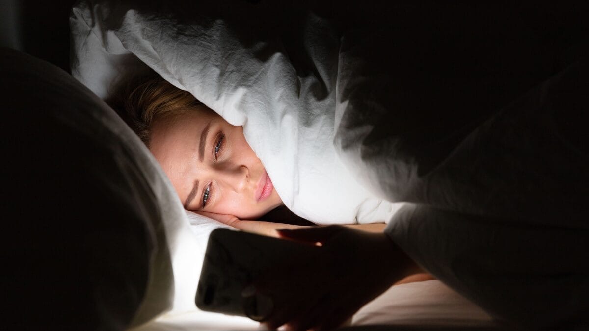 Insônia | Mulher na cama olhando o celular | dormir | Foto: banco de imagens